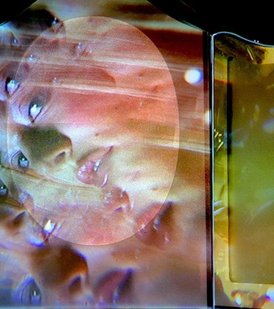 A distorted and multi-layered image of a face projected on transparent surfaces.