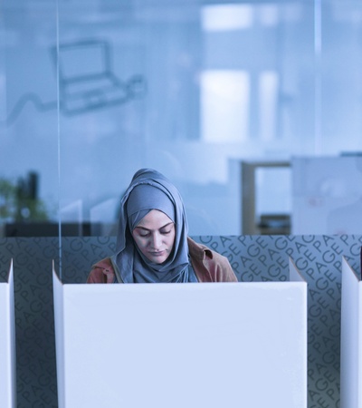 Three women are working quietly in a modern office space with cubicles.