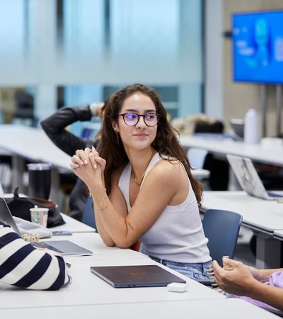 A group of students engaged in a discussion around a table in a classroom setting.