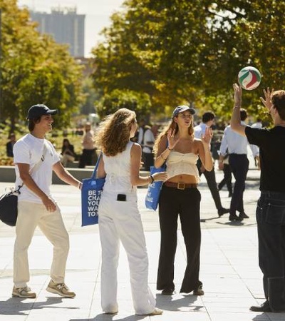 Group of people casually playing with a soccer ball in a sunny urban square.