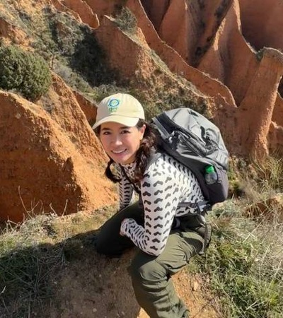 A person is hiking in a rugged landscape with orange rock formations.