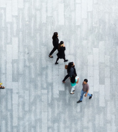 Aerial view of multiple people walking on a patterned pavement.