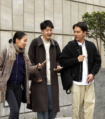 A group of young adults walking and talking together in an urban setting.