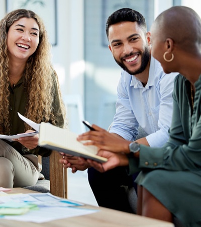 Three professionals sitting and discussing with documents on a table in a well-lit office.