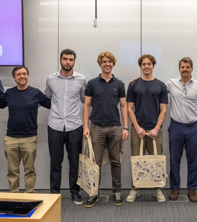 A group of young men stands together in a conference room for a photo.