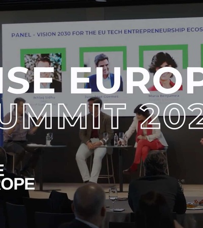 A conference room with people attending the RISE Europe Summit 2024, featuring panel discussions on technology and entrepreneurship.