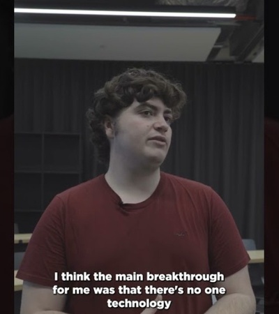 A young man in a red shirt speaks during an interview, with a caption about technology breakthroughs visible.