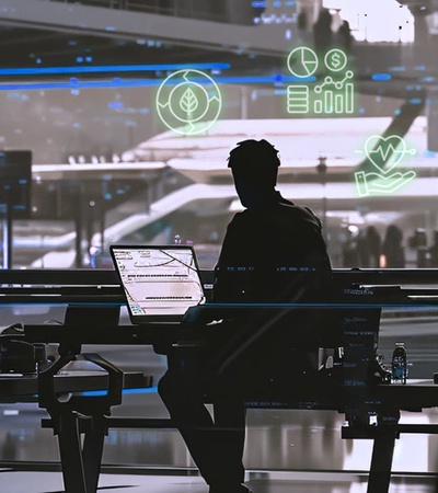 A silhouette of a person sitting at a desk with digital screens and futuristic elements in the background.