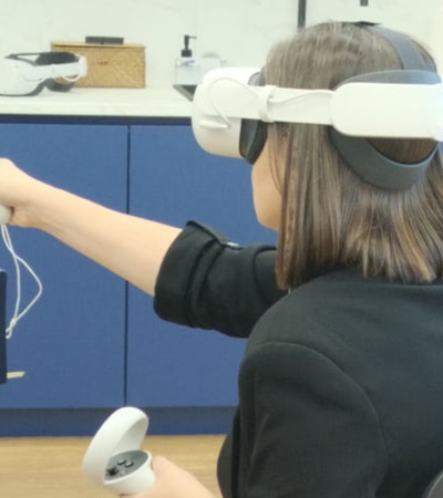 A person wearing a virtual reality headset is interacting with a digital environment using handheld controllers.