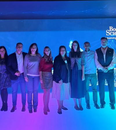 A group of people standing under blue lighting at a Boston Scientific event.