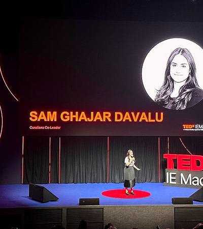 A speaker presenting at a TEDx event on stage.