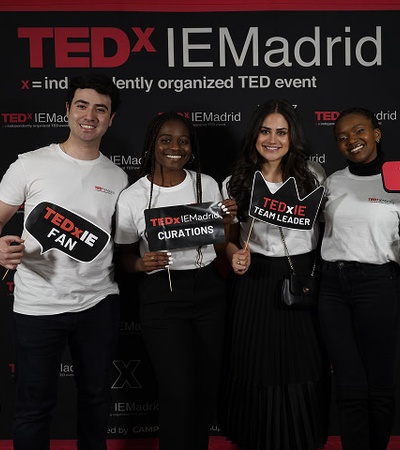 A group of four people posing with signs at a TEDx event in Madrid.