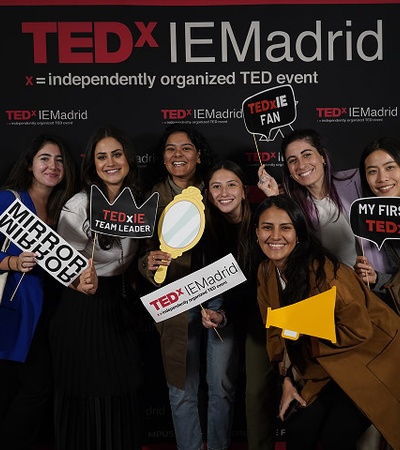 A group of smiling women holding signs at a TEDx event in Madrid.