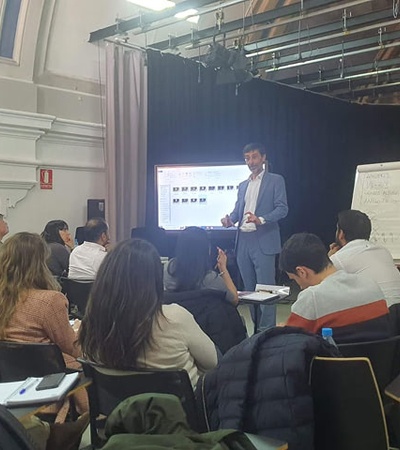 A speaker presents to an audience in a seminar setting.