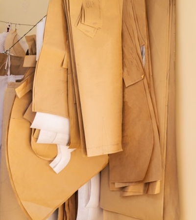 A collection of pattern papers and fabric cuttings hanging on a rack in a fashion design studio.