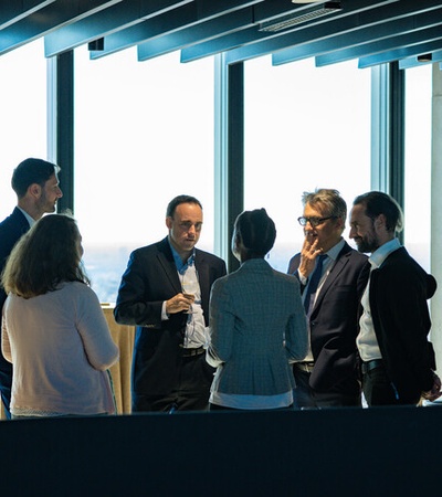 A group of professionals engaged in conversation at a modern office setting with a city view.