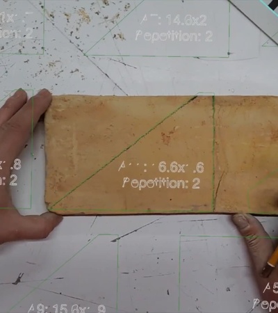 A person is measuring and marking a rectangular piece of material on a table.