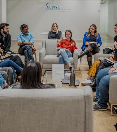 A diverse group of people sitting in a circle engaged in a discussion in a modern indoor setting.