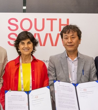 Four people standing in front of a 'South by Southwest' sign, holding documents and smiling for the camera.
