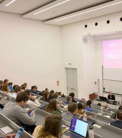 A panel discussion taking place in an auditorium with an audience and speakers.