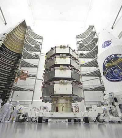 A large spacecraft being prepared for launch in a clean room environment.
