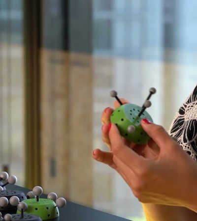 A person holding a colorful toy resembling a molecule while interacting with others on a table.