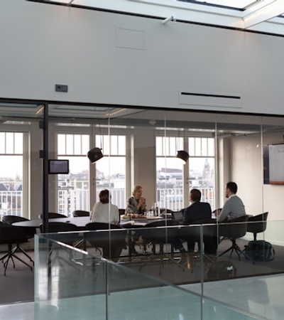 A group of professionals is having a meeting in a modern glass-walled conference room.