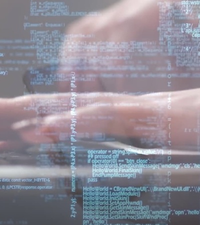 A person's hands typing on a laptop surrounded by digital code.