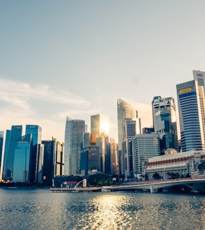 A stunning view of a modern city skyline illuminated by the sun beside a calm water body.