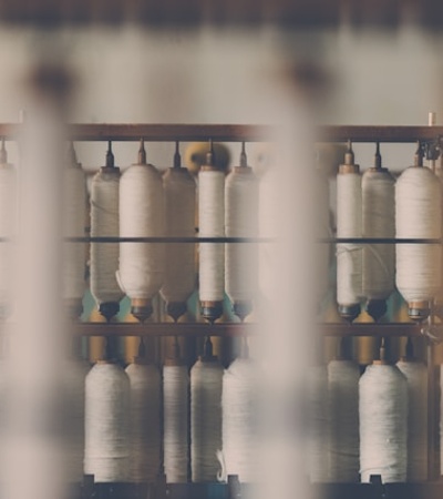 A blurred view of spools of thread on racks in a textile manufacturing setting.