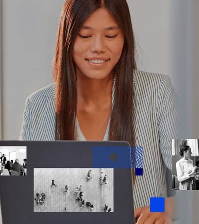 A woman working on her laptop with multiple images of various scenes displayed in the background.