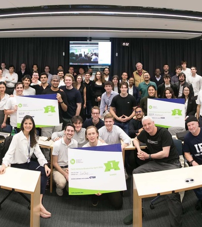 A group of people posing in a classroom environment, holding certificates and smiling at the camera.