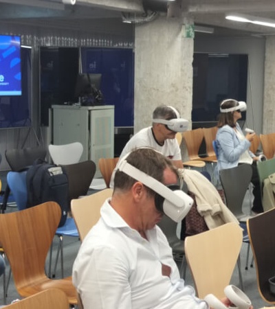 A group of people sitting in a conference room, wearing virtual reality headsets.