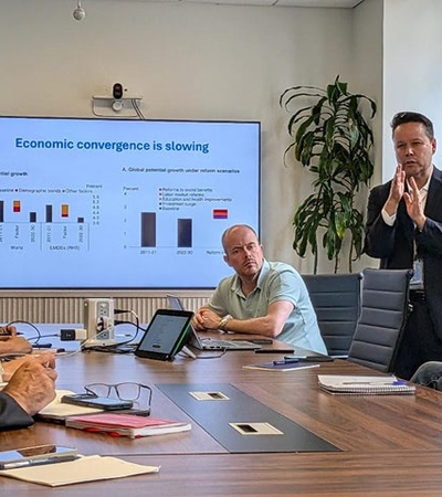 A business meeting discussing economic convergence with a presentation displayed.