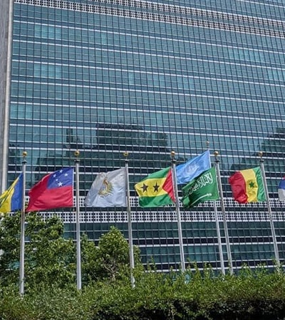 A view of the United Nations building with several flags from different countries in front.