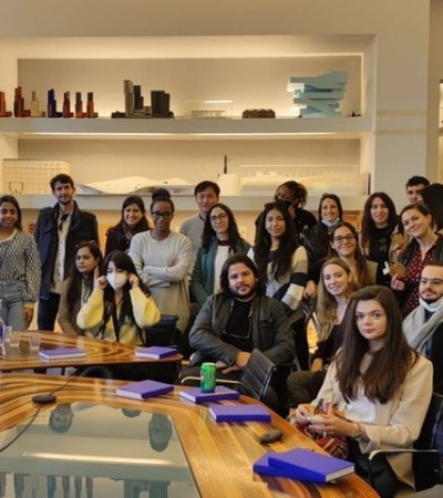 A diverse group of people gathered in a contemporary meeting room with architectural models in the background.