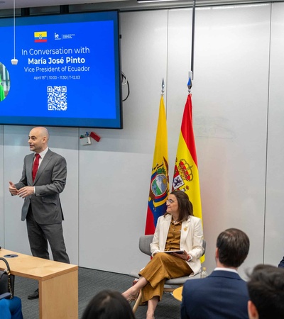 A panel discussion featuring Maria Jose Pinto, the Vice President of Ecuador, at an event with national flags in the background.