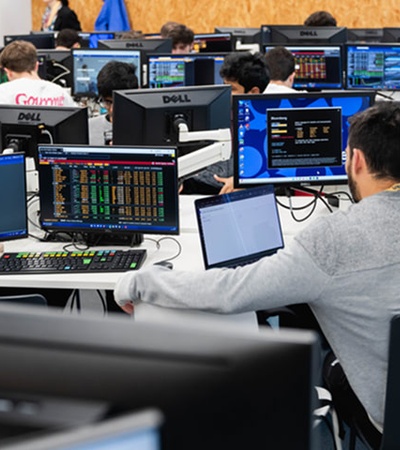 The image shows a group of people working at computers in a modern office environment.