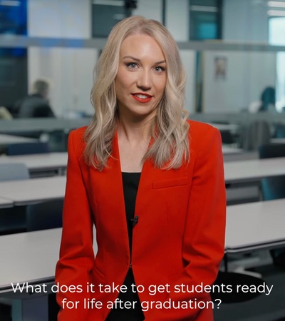 A woman in a red jacket speaks about preparing students for life after graduation.