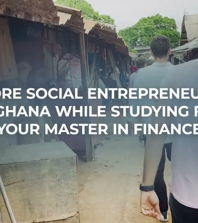 Two people walking through an outdoor market area with text advertising master's degree opportunities in finance and social entrepreneurship in Ghana.