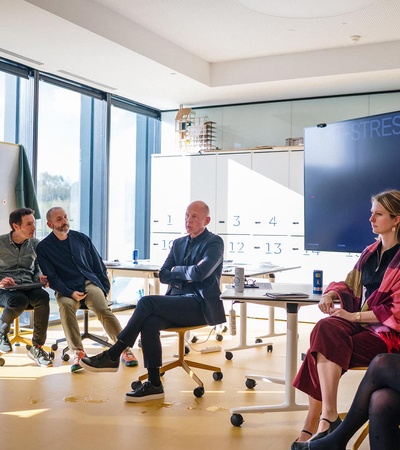 A group of people are engaged in a discussion in a modern office setting.