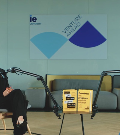 Three people are seated in a modern meeting room engaged in a podcast discussion.