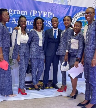A group of seven women and one man posing in front of a banner that reads 'President's Young Professionals Program (PYPP)'.