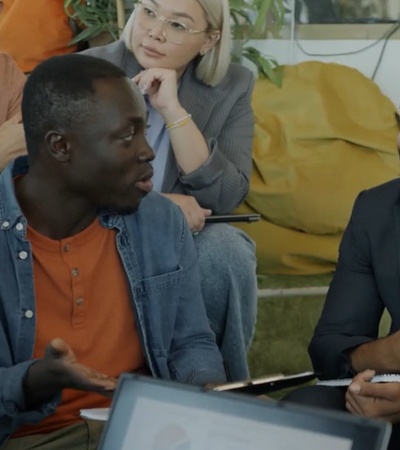 A diverse group of professionals engaging in a discussion in a bright, open workspace.