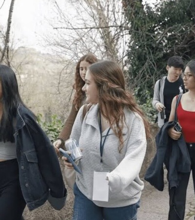 A group of young women walking together along a roadside, engaged in conversation.