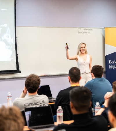 A woman is giving a presentation in a classroom filled with attentive students.