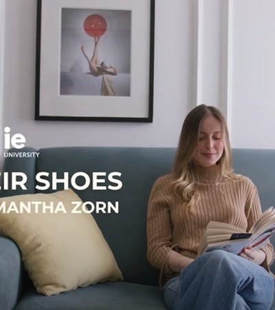 A young woman is sitting on a couch reading a book in a cozy living room.