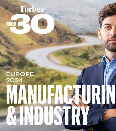 A confident young man stands in front of a scenic background, showcasing innovation in manufacturing and industry.
