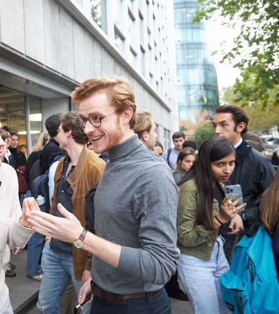 Three people are engaging in a conversation on a busy city street.