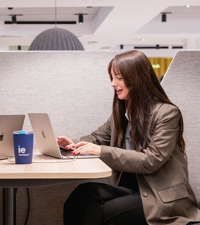 Two people are working on laptops at a table in a modern cafe.